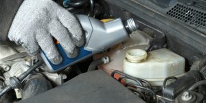 Auto mechanic topping up brake fluid in the vehicle